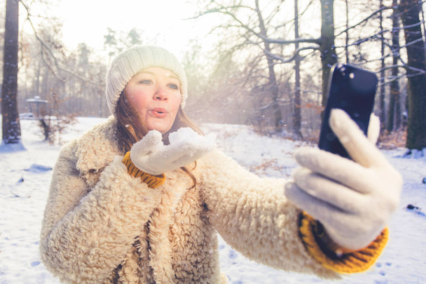 beautiful smiling young woman taking selfie with smartphone in winter forest - Foto, Bild