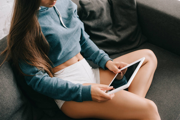обрезанный вид девушки в трусиках с помощью цифрового планшета на диване
 - Фото, изображение