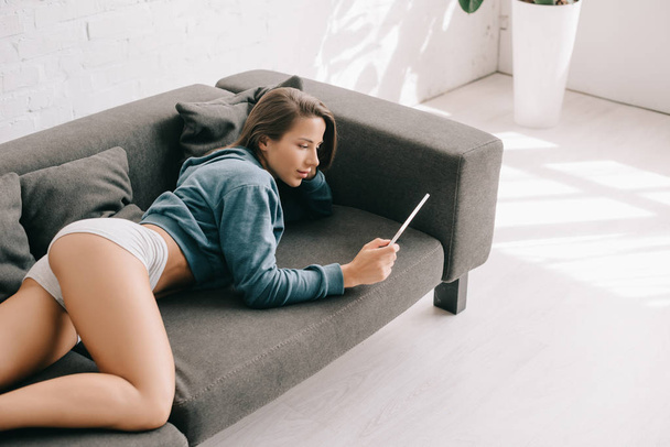 attractive sexy woman in panties using digital tablet on sofa - Photo, Image