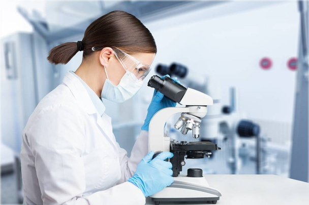Mujer joven usando microscopio en laboratorio
 - Foto, imagen