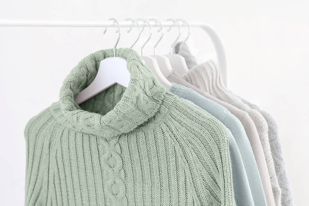 Tranquil menta verde suéteres calientes de punto en perchas blancas
. - Foto, imagen