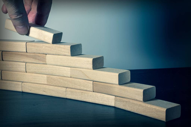 Hand stapelen houten blokken in de vorm van trappen. Bedrijfsconcept voor succesvolle proces groei. - Foto, afbeelding