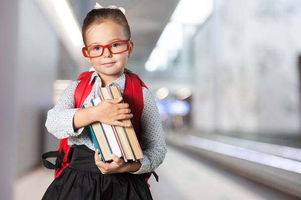Little schoolgirl with books looking at camera - Valokuva, kuva