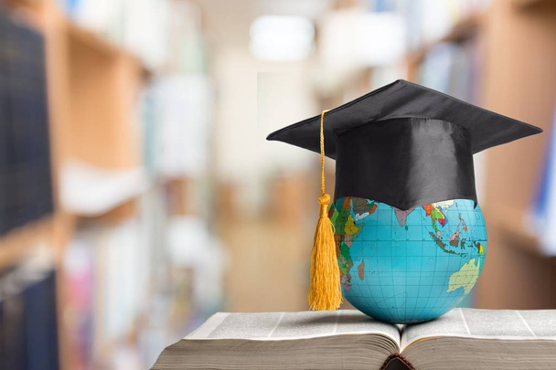 globe in graduation hat on table and book - Photo, Image