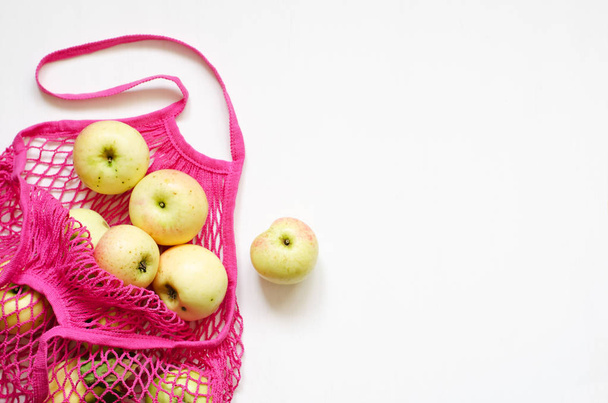 Sac à provisions en maille rose avec pommes fraîches sur fond blanc en bois
 - Photo, image