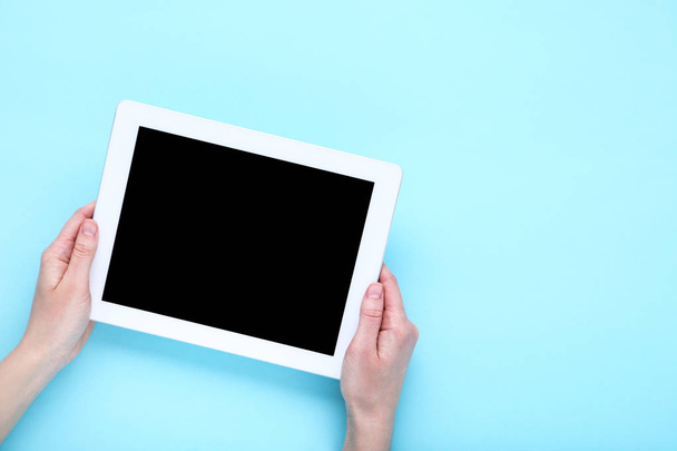 Tablet computer in female hands on blue background - 写真・画像