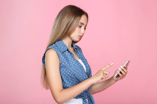 Beautiful young woman using mobile phone on pink background - Φωτογραφία, εικόνα