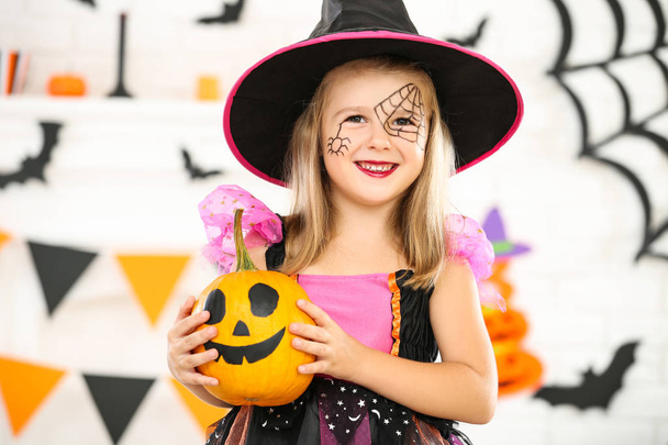 Young girl in halloween costume holding orange pumpkin - Fotoğraf, Görsel