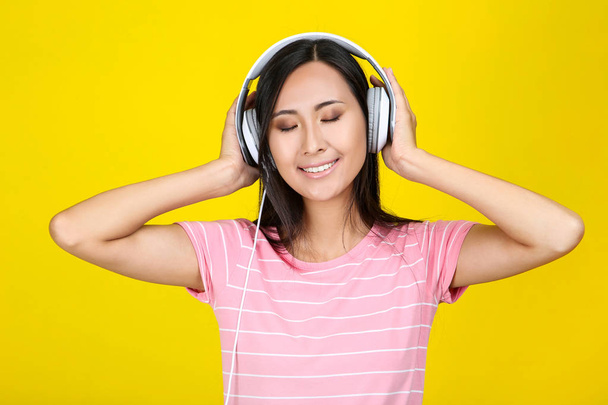 Beautiful woman with headphones on yellow background - Photo, Image
