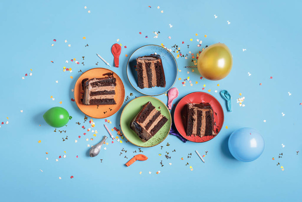 Rebanadas de pastel de chocolate en platos coloridos y decoración del partido
 - Foto, imagen