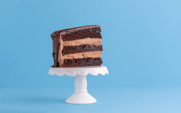 Slice of chocolate layered cake on white dessert stand - Photo, Image