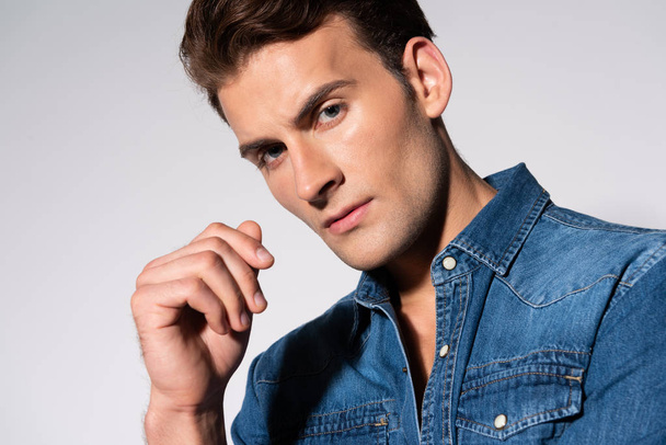 handsome man in denim shirt looking at camera on white  - Foto, afbeelding
