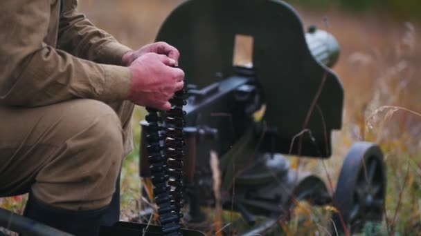 Een man soldaat bereidt de munitie voor op de lading in het machinegeweer - zet de patroons op hun plaats - Video