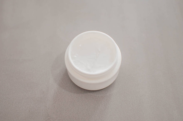 Una crema di bellezza su un contenitore di plastica su sfondo grigio
 - Foto, immagini