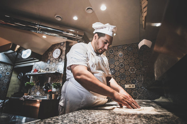 Chef is making pizza at the restaurant kitchen - Foto, Imagen