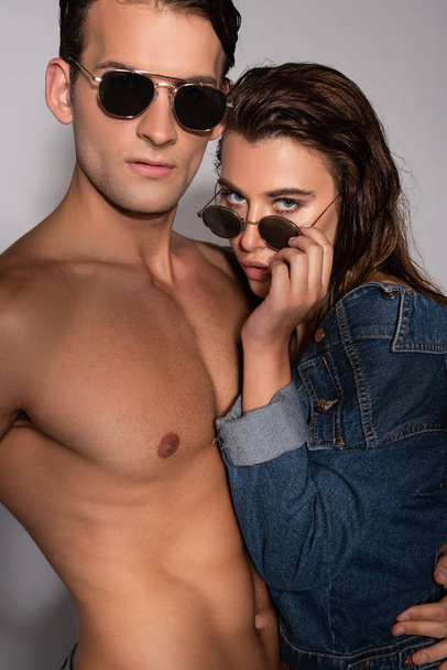 stylish girl touching sunglasses near muscular boyfriend on white  - 写真・画像