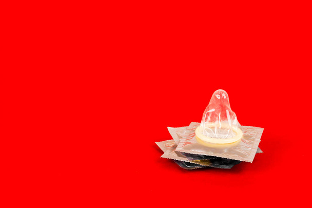 赤の背景にコンドーム。安全なセックスの概念 - 写真・画像