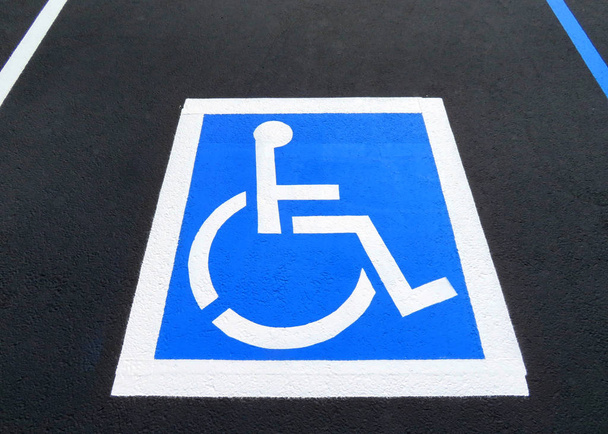 Świeżo wyremontowane i przemalowane miejsce parkingowe dla niepełnosprawnych na parkingu. Liczba miejsc dla niepełnosprawnych wzrasta wraz z wielkością partii, co wymaga mniej więcej jednego miejsca dla niepełnosprawnych na 25 miejsc.. - Zdjęcie, obraz