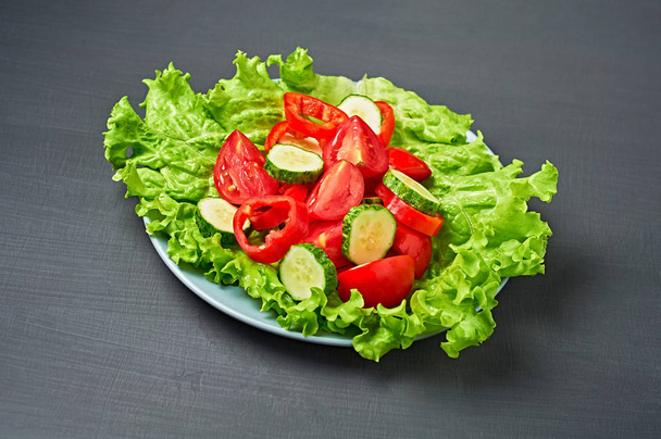 Volledige plaat caloriearme salade met tomaat, peper, komkommer ligt op gekrast donker beton. Vegetarisch, dieet, gezond voedsel. Close-up - Foto, afbeelding