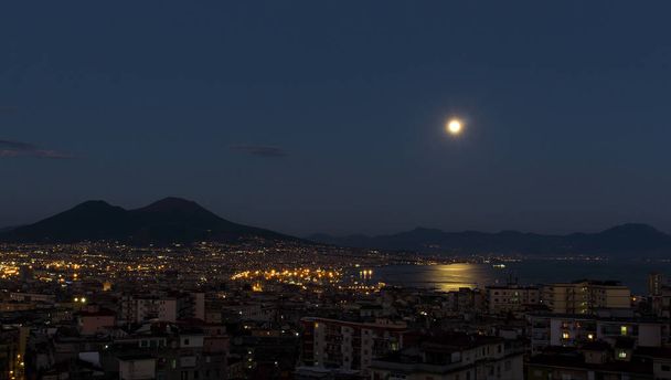 Napels met Vesuvius 's nachts gefotografeerd met maan weerspiegeld in de zee - Foto, afbeelding