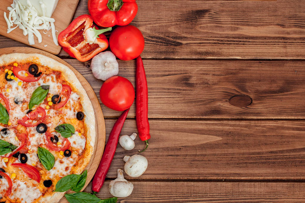 Pizza Margherita or Margarita with Mozzarella cheese, tomato, olive. Italian pizza on wooden background - Foto, imagen