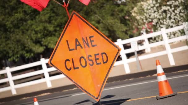 Lane zamknięty znak z pomarańczowymi flagami i stożkami na drogach - Materiał filmowy, wideo
