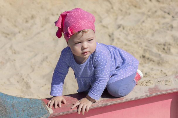 Pieni tyttö sinisessä mekossa seisoo kaikki neloset hiekkalaatikon reunalla, kesäinen aurinkoinen päivä kävely
 - Valokuva, kuva