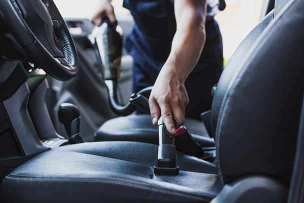 cropped view of car cleaner vacuuming drivers seat in car - 写真・画像