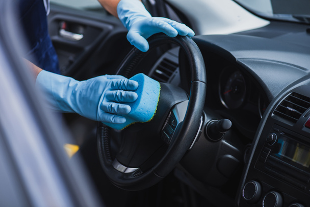 selective focus of car cleaner wiping steering wheel with sponge - Foto, immagini