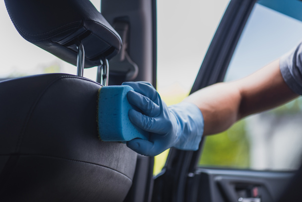 partial view of car cleaner wiping car seat with sponge - Foto, afbeelding