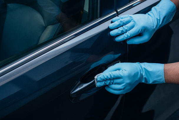 partial view of car cleaner polishing black car door handle  - Foto, afbeelding