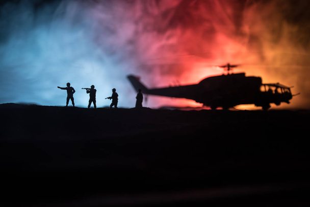 軍用ヘリコプター紛争地帯からを飛行する準備ができてのシルエット。霧のトーン バックライト付きの砂漠で始まるヘリコプター飾られて夜の映像。選択と集中. - 写真・画像