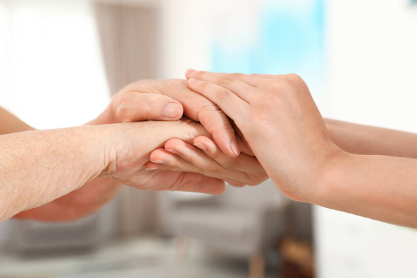 Ihmiset pitävät toisiaan kädestä hämärtyneellä taustalla, lähikuvassa. Apua ja vanhustenhuoltoa
 - Valokuva, kuva
