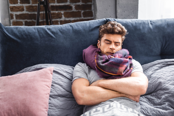 sick and handsome man in scarf lying in bed  - Photo, Image