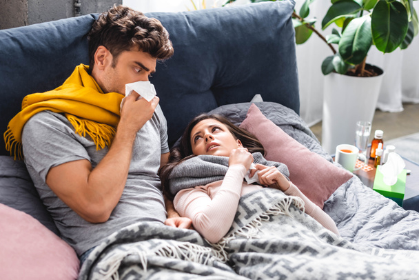 sick girlfriend and handsome boyfriend sneezing and holding napkins  - Photo, Image