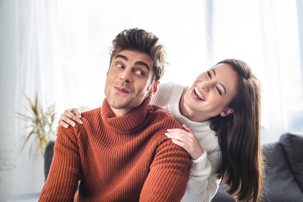 attrayant petite amie et petit ami en chandails souriant et câlin dans l'appartement
  - Photo, image
