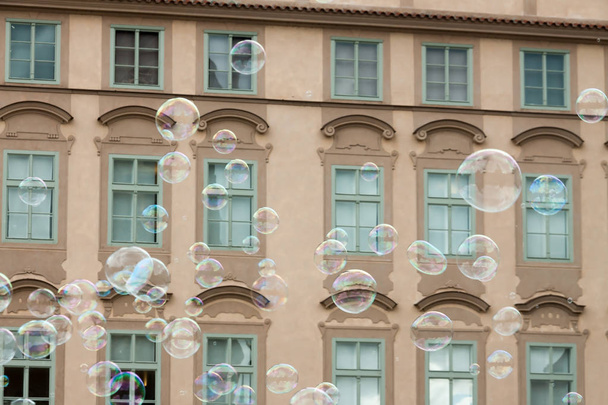 lots of transparent colorful soap bubbles brown facade building background European house - Foto, Imagen
