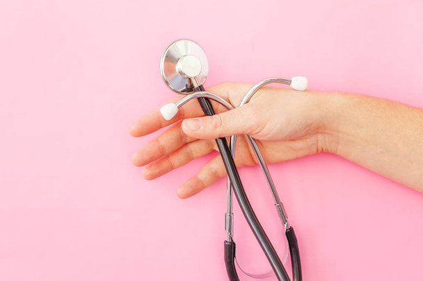 Simply minimal design woman hand holding medicine equipment stethoscope or phonendoscope isolated on trendy pastel pink background - Foto, afbeelding