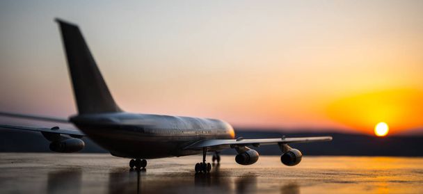 Kunstwerk decoratie. Witte passagiersvliegtuig klaar om opstijgen van de landingsbaan van de luchthaven. Silhouet van vliegtuigen tijdens zonsondergang tijd. - Foto, afbeelding