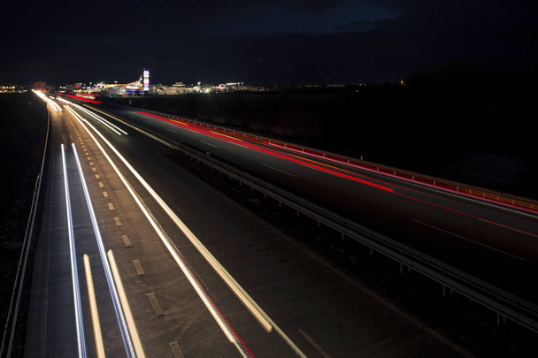 Bewegung verschwommene Lichtspuren, die in die Dunkelheit des Autobahnverkehrs in die Stadt kurz nach Sonnenuntergang leuchten. - Foto, Bild