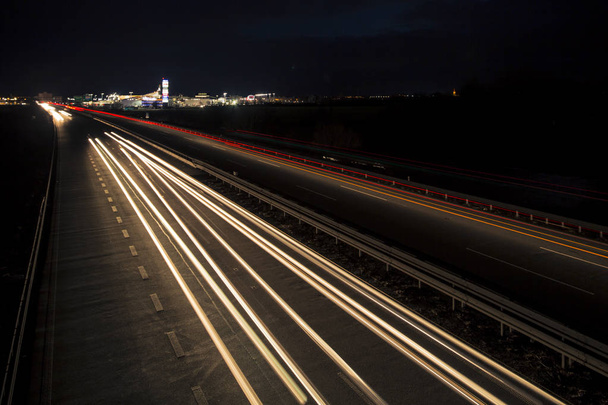 Pohyb rozmazané světelné stopy zářící do tmy dálniční dopravy do města těsně po západu slunce. - Fotografie, Obrázek