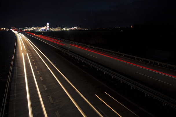 Beweging wazig licht tracks gloeien naar de duisternis van de snelweg verkeer naar de stad net na zonsondergang. - Foto, afbeelding