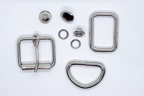 Set of metal accessories for the manufacture of collars for dogs on a white background. Iron frame, half ring, buckle, grommet and rivet for backpack straps. Accessories from metal set. - Photo, Image