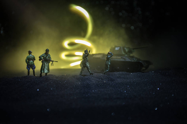 Gevechtsscène. Militaire silhouetten vechten scène op oorlog mist hemel achtergrond. Een Duitse soldaat verhoogde de armen tot overgave. Plastic speelgoed soldaten met geweren die de vijandelijke soldaat gevangen nemen. - Foto, afbeelding
