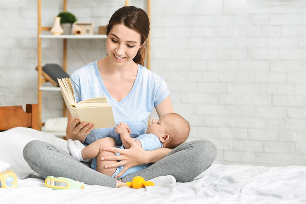Young mom reading book to her infant baby - 写真・画像