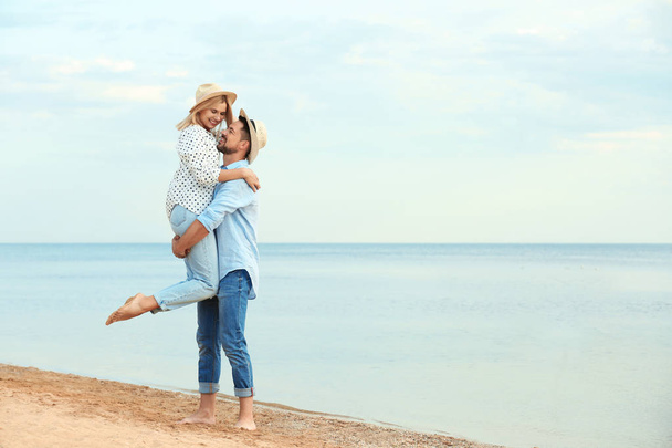 Happy romantic couple spending time together on beach, space for text - Foto, afbeelding