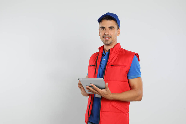 Happy young courier with tablet on white background - Φωτογραφία, εικόνα