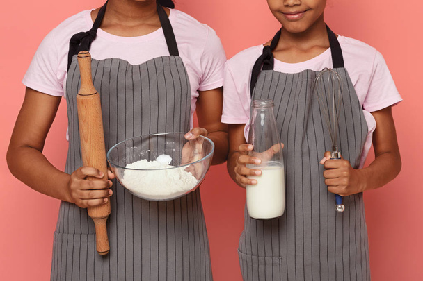 Imagen recortada de hermanas negras sosteniendo herramientas de cocina
 - Foto, imagen