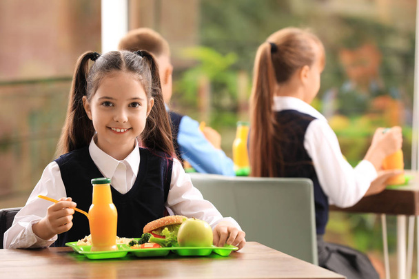 学校の食堂で健康的な食べ物とテーブルで幸せな女の子 - 写真・画像