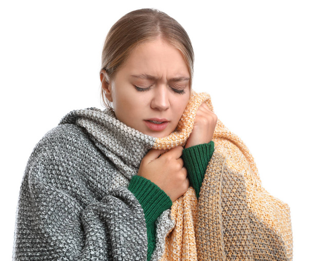 Young woman wrapped in warm blanket suffering from cold on white background - Photo, image